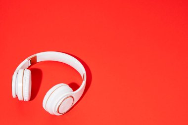 Kırmızı arka planda beyaz kablosuz kulaklıklar. Müzik konsepti 