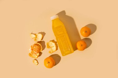 Plastik şişede detoks içeceği, bej arka planda mandalina. Üst görünüm, düz uzanma