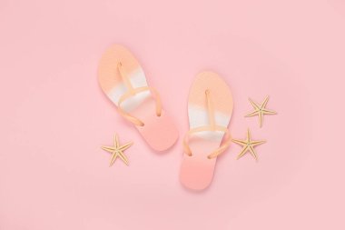 Plaj terlikleri, pembe arka planda deniz yıldızları. Üst manzara, düz uzanma 