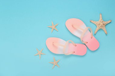 Plaj terlikleri, mavi arka planda deniz yıldızı. Üst manzara, düz uzanma
