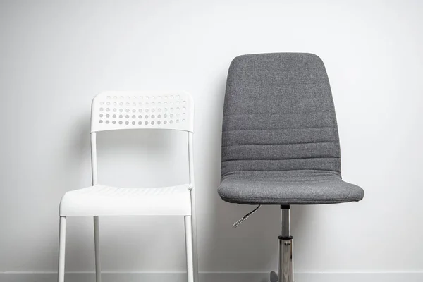 白いプラスチック製の椅子 白い壁の背景にファブリックオフィスチェア — ストック写真