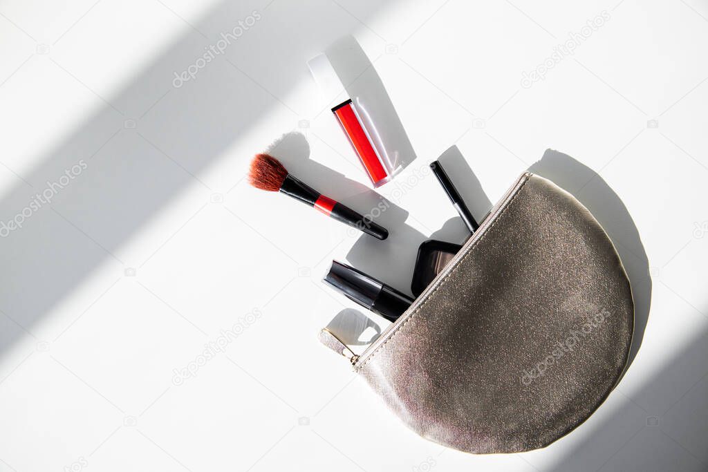 Cosmetic bag with mascara and makeup cosmetics on a white table in the morning sun. Flat lay, top view.