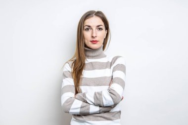 Hafif arka planda çizgili süveter giyen, hafif makyajlı genç bir kadın.