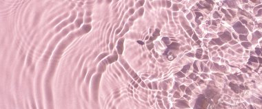 Güneş ışığı altındaki pembe suyun üzerindeki damlalardan gelen doku dalgaları. Üst manzara, düz yatış. Pankart.