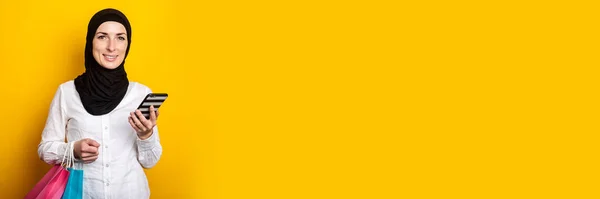 Самка Юна Мусульманка Хіджабі Тримає Телефонні Торгові Сумки Жовтому Тлі — стокове фото