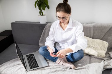 Kanepede otururken dizüstü bilgisayarı olan genç bir kadın.