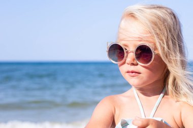 Güneşli bir günde plajda güneş gözlüklü güzel bir kız. 