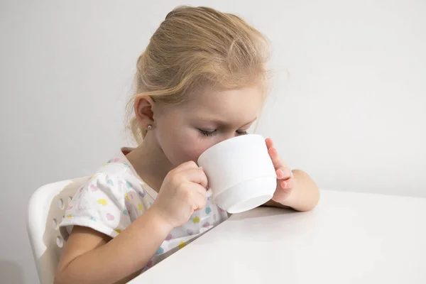 Beautiful Child Girl Blonde Drinks White Cup White Table — стоковое фото