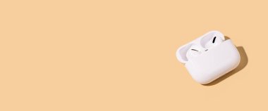 Bej arka planda kablosuz kulaklık. Düz yerde, üst tarafta. Pankart 