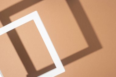 Açık kahverengi arka planda beyaz podyum çerçevesi. Üst manzara, düz uzanma.