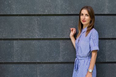 Taş bir duvarın arkasında giyinmiş, dost canlısı genç bir kadın..
