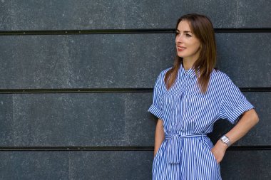 Taş bir duvarın arkasında giyinmiş, dost canlısı genç bir kadın..