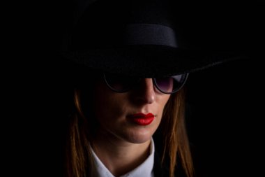 Siyah şapkalı ve siyah arka planda gözlüklü güzel bir kadın..