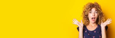 shocked surprised beautiful curly young woman on a yellow background. Banner