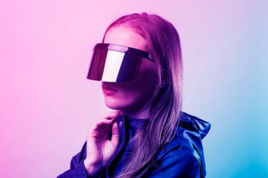 VR gözlüklü ve mavi ceketli genç bir kadın arka planda hafif bir eğim eklemiş.. 
