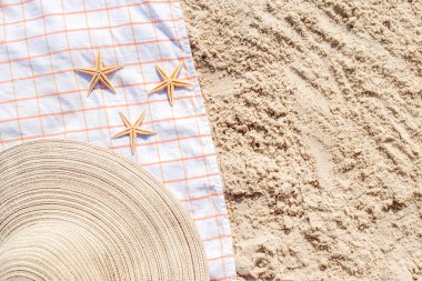 Altın denizyıldızı, kumlu sahilde şapka. Üst manzara, düz uzanma. 