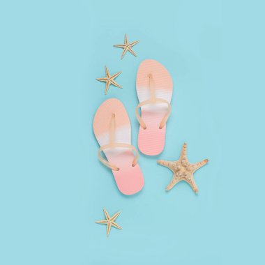 Plaj terlikleri, mavi arka planda deniz yıldızı. Üst manzara, düz uzanma