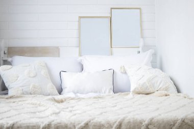 Yatak odasında hafif ekose örülü rahat bir yatak ve duvarında iki boş resim var..