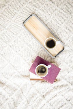 İki fincan kahve, arka planda hafif örülmüş kitaplar. Üst manzara, düz uzanma.