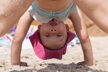 Sahilde mayo giymiş neşeli bir kız çocuğu oynanıyor.