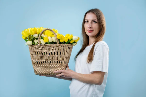 Mujer Joven Sonriente Sosteniendo Tulipanes Amarillos Canasta Sobre Fondo Azul — Foto de Stock