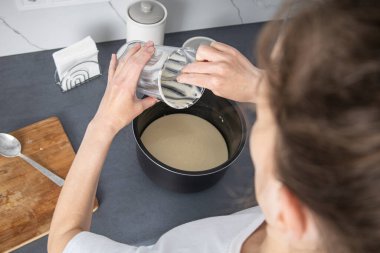 Kadın kaseden yemek kabına hamur döküyor. Üst manzara, düz uzanma.