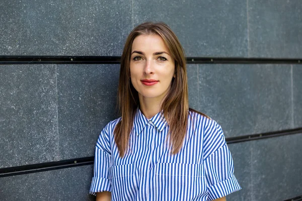 Taş bir duvarın arkasında giyinmiş, dost canlısı genç bir kadın..