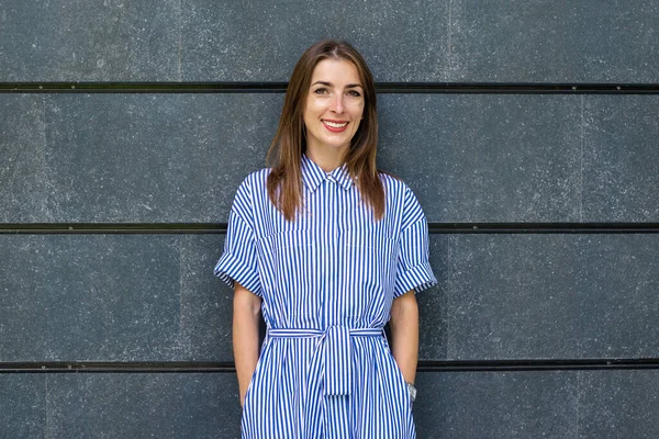 Taş bir duvarın arkasında giyinmiş, dost canlısı genç bir kadın..