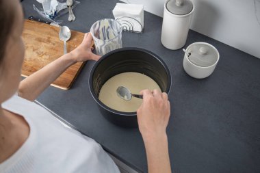 Kadın fırın tabağına hamur döküyor. Üst manzara, düz uzanma.