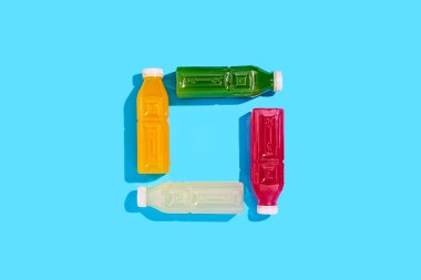 Mavi arka planda plastik şişelerde detoks suyu içeceği. Üst manzara, düz uzanma