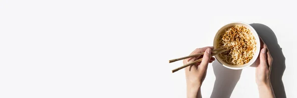 女性の手は白い背景に段ボールのボウルに中華麺を保持します トップビュー フライレイ バナー — ストック写真