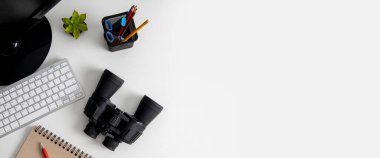 Dürbünler beyaz arka planda bilgisayarın yanında duruyor. Üst manzara, düz yatış. Pankart.