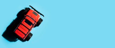 Toy red jeep car on a blue background. Top view, flat lay. Banner.