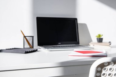 Pencerenin yanında bilgisayar ve ofis malzemeleri olan rahat modern çalışma alanı 