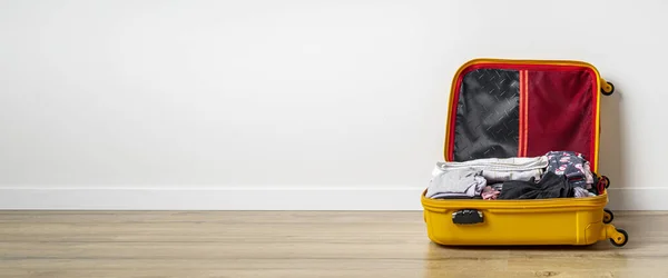 Yellow Suitcase Clothes Wooden Floor White Wall Banner — Stock fotografie