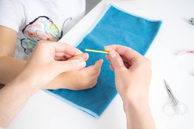 Women's hands on a child's hand file their nails with a nail file. Top view, flat lay.