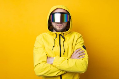 Young man in virtual reality glasses in a yellow jacket on a yellow background.