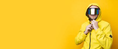 Young man in cyberpunk glasses in a yellow jacket on a yellow background. Banner.