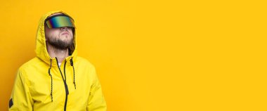 Young man in virtual reality glasses looks up on a yellow background. Banner.