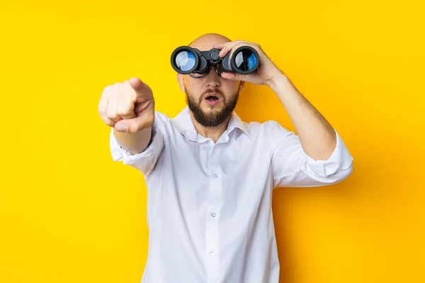 Surprised Young Man Looking Binoculars Pointing His Finger Front Yellow — Stok fotoğraf