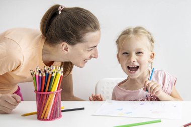 A joyful girl child with a mother is painted with colored pencils on paper.