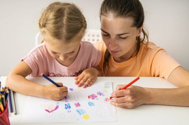 Smiling mother and daughter drawing together with colored pencils on paper. Top view, flat lay.