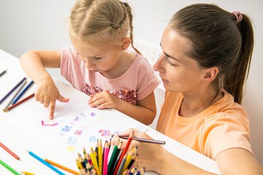Mother and daughter drawing together with colored pencils on paper. Top view, flat lay.