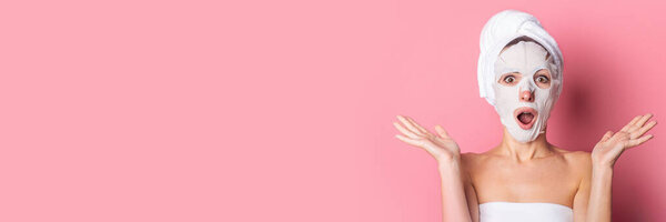 surprised young woman with a cosmetic mask on her face on a pink background, skin care. Banner