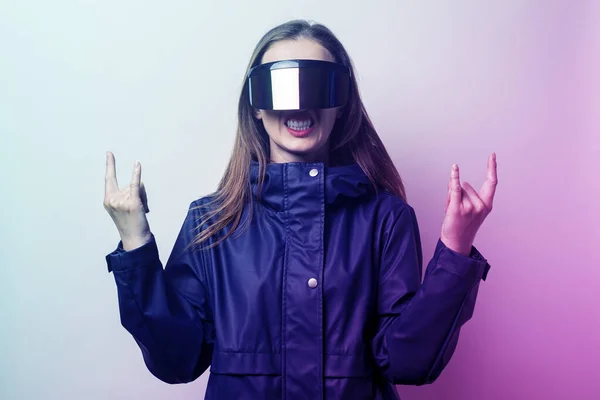 Young woman with glasses of virtual reality shows rocker goat, added gradient on a light background.