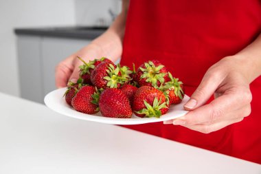 Mutfakta çilekli bir tabak tutan kadın eller..