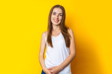 Sarı arka planda uzun saçlı, gülümseyen güzel bir genç kadın..