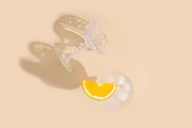 Bej arka planda bir bardakta portakal dilimli kokteyl. Üst manzara, düz uzanma.