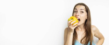 Beyaz arka planda taze sarı biber yiyen genç bir kadın. Pankart.