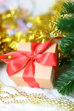 Yılbaşı ve Sevgililer Günü için Noel ağacının yanında, arka planında kırmızı bir fiyonk olan güzel bir sürpriz hediye kutusu.